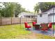 Backyard featuring an outdoor seating area with red chairs, a green lawn, and a wood fence at 1510 Mobile Ave, Tampa, FL 33610