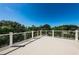 Spacious patio with white cable railing and tropical tree line in distance at 160 Shore Dr, Palm Harbor, FL 34683