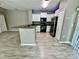 Modern kitchen with white cabinets, black appliances, and wood-look flooring, creating a sleek and inviting space at 1878 Greenwood Valley Dr, Plant City, FL 33563