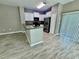 Bright kitchen with white cabinets, black appliances, and breakfast bar overlooking living area with wood-look floors at 1878 Greenwood Valley Dr, Plant City, FL 33563