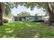 Expansive backyard featuring mature landscaping, manicured lawn and a screened-in porch at 1960 Canadiana Ct, Dunedin, FL 34698