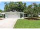 Charming single-story home with a well-manicured lawn, mature trees and a two car garage at 1960 Canadiana Ct, Dunedin, FL 34698