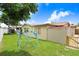Spacious backyard featuring a climbing structure, lush green grass, and privacy fencing at 2119 Sugarbush Dr, Holiday, FL 34690