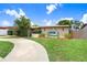 Inviting single-story home with mature landscaping, a circular driveway, and unique architectural details at 2119 Sugarbush Dr, Holiday, FL 34690