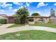 Beautiful single-story home featuring mature landscaping, a circular driveway, and a unique arched entryway at 2119 Sugarbush Dr, Holiday, FL 34690