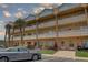 A tan condominium building is shown with palm trees, balconies, and tropical plants at 2466 Ecuadorian Way # 32, Clearwater, FL 33763