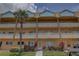 A tan condominium building with palm trees, balconies, and colorful plants sits beneath a partially cloudy sky at 2466 Ecuadorian Way # 32, Clearwater, FL 33763