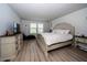 Bright main bedroom with luxury chaise, light walls, wood-look flooring, and sunny window at 26082 Woven Wicker Bnd, Lutz, FL 33559