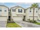 This exterior shot showcases a modern townhome with a one-car garage and beautiful landscaping at 26082 Woven Wicker Bnd, Lutz, FL 33559