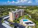 Aerial view of a high-rise condo building with a swimming pool, parking, and surrounding green landscape at 2621 Cove Cay Dr # 309, Clearwater, FL 33760