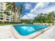 Beautiful community pool reflecting the sky, surrounded by lounge chairs and mature palm trees at 2621 Cove Cay Dr # 309, Clearwater, FL 33760