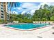 Large community pool with lounge chairs surrounded by mature trees and palm trees at 2621 Cove Cay Dr # 309, Clearwater, FL 33760