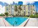 Exterior view of a large pool and surrounding multi-story building and palm trees at 2621 Cove Cay Dr # 309, Clearwater, FL 33760