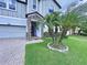 Welcoming front entrance featuring a stone facade and a beautifully landscaped yard with a mature palm tree at 2798 Hilliard Dr, Wesley Chapel, FL 33543