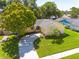 Beautiful aerial view of the house showcasing the driveway, lush lawn, and mature trees enhancing curb appeal at 310 Arbor E Dr, Palm Harbor, FL 34683