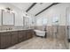 Luxurious bathroom with double vanity, soaking tub, wood tile flooring, and elegant lighting fixtures at 311 12Th N Ave, St Petersburg, FL 33701