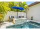Backyard pool area features a fire pit sitting area with a blue umbrella and lush tropical landscaping at 311 12Th N Ave, St Petersburg, FL 33701