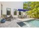 Backyard pool area features travertine tile, dining set with blue umbrella, and lush tropical landscaping at 311 12Th N Ave, St Petersburg, FL 33701