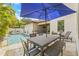 Inviting backyard pool area features travertine tile, dining set with blue umbrella, and lush tropical landscaping at 311 12Th N Ave, St Petersburg, FL 33701