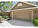 Attached two-car garage featuring brick accents, a paved driveway, and manicured landscaping at 344 Cascade Ln, Palm Harbor, FL 34684