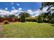 Well-maintained backyard with lush green grass, mature trees, and a privacy fence providing a serene outdoor space at 408 River Bed Ct, Wimauma, FL 33598