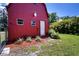 Close-up of a red barn featuring two windows and a white door surrounded by decorative agave plants and lush greenery at 408 River Bed Ct, Wimauma, FL 33598
