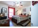 Bedroom with wood floors, ceiling fan, and large window with red curtains at 408 River Bed Ct, Wimauma, FL 33598