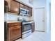 Kitchen with stainless steel appliances, wooden cabinets, and a view of the stove and microwave at 4116 Knollpoint Dr, Wesley Chapel, FL 33544