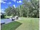 Outdoor stone patio has wicker furniture with plush cushions surrounded by a green lawn and mature trees at 4116 Knollpoint Dr, Wesley Chapel, FL 33544