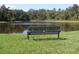 A peaceful community pond view with a bench that allows residents to sit, relax and enjoy the surrounding nature at 4116 Knollpoint Dr, Wesley Chapel, FL 33544