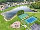 Aerial view showcasing community amenities including a lake, tennis court, and playground at 4901 Windingbrook Trl, Wesley Chapel, FL 33544