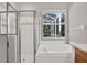 Bathroom with a glass-enclosed shower and a large soaking tub overlooking the outdoors at 4901 Windingbrook Trl, Wesley Chapel, FL 33544