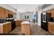 Open concept kitchen with wood cabinets, black appliances, kitchen island, and wood-look tile flooring at 4901 Windingbrook Trl, Wesley Chapel, FL 33544