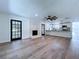 Open living room with a fireplace, wood flooring, ceiling fan, and black french doors to the outside at 5007 Booth Rd, Plant City, FL 33565