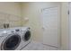 Well-lit laundry room featuring a white washer and dryer set, wire shelving and white tiled flooring at 5315 Cedarshake Ln, Valrico, FL 33596