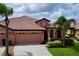 Inviting single-story home showcasing lush landscaping, terracotta roof and a spacious two-car garage at 5663 Sunset Falls Dr, Apollo Beach, FL 33572