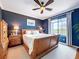 Stylish main bedroom with dark blue walls, wood furniture, and a large window at 5663 Sunset Falls Dr, Apollo Beach, FL 33572