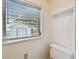 This cozy bathroom features a toilet, shelf, and a window at 5906 12Th St, Zephyrhills, FL 33542