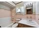 Bathroom with pink and white tile, a bathtub, toilet, and vanity with a single sink at 5906 12Th St, Zephyrhills, FL 33542