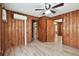 Hallway with wood-paneled walls and tiled floors leading to multiple rooms with wood doors at 5906 12Th St, Zephyrhills, FL 33542