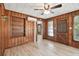 Living room featuring wood-paneled walls, built-in shelves, tiled floors, and a window air conditioner at 5906 12Th St, Zephyrhills, FL 33542