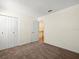 Bedroom with neutral carpet, a closet with white paneled doors, and a view to the staircase at 6114 Oak Cluster Cir, Tampa, FL 33634
