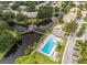 Aerial view showcasing a pool and clubhouse area, with a footbridge over a river and nearby neighborhood at 6206 92Nd N Pl # 3605, Pinellas Park, FL 33782