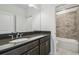 Well-lit bathroom with a dark vanity, elegant countertop, and tiled shower with a built-in niche at 7024 Bradbury Cir, Wesley Chapel, FL 33545