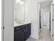 Modern bathroom features a vanity with dark cabinets and a white countertop next to a bathroom with tile at 7024 Bradbury Cir, Wesley Chapel, FL 33545
