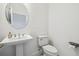 Classic pedestal sink and toilet with round mirror create a bright half bathroom at 7024 Bradbury Cir, Wesley Chapel, FL 33545