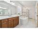 Bright bathroom with a soaking tub, shower, and wood cabinets at 7024 Bradbury Cir, Wesley Chapel, FL 33545