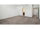 Well-lit bedroom features neutral carpet and white walls, next to a doorway leading to an adjacent bathroom at 7024 Bradbury Cir, Wesley Chapel, FL 33545