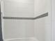 Bright and clean bathroom tub-shower is decorated with horizontal line of decorative tile and white subway tile at 7024 Bradbury Cir, Wesley Chapel, FL 33545