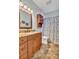 Bathroom with vanity, wood cabinets, granite countertop, decorative mirror, and shower-tub combination at 9242 Brindlewood Dr, Odessa, FL 33556